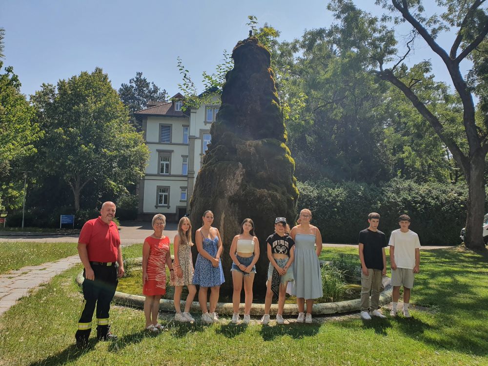 Die Gruppe steht vor dem Brunnen im Gelände